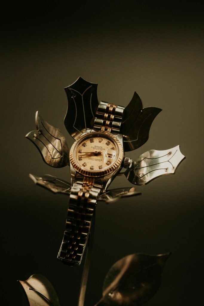 Gold watch artfully displayed on metallic flower, creating a luxurious and unique composition.